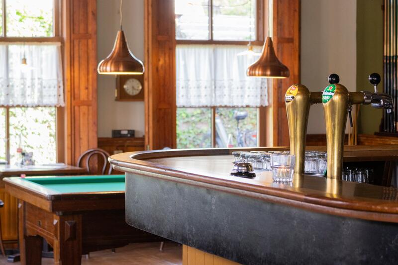 De koperen bar met biertaps en de biljarttafel in het café